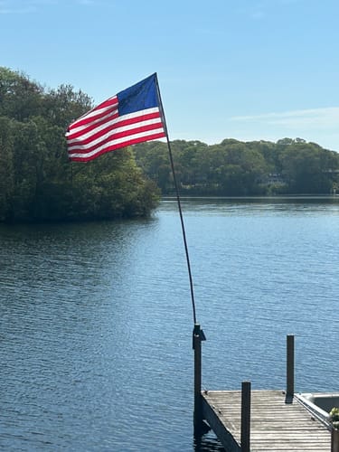 Reviewer's Betsy Ross Flag seen from the back, flying on a pole over water on a sunny day.