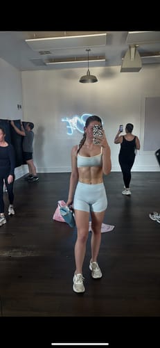 Customer wearing the ice-blue Essentials Short as part of a workout set in a studio.
