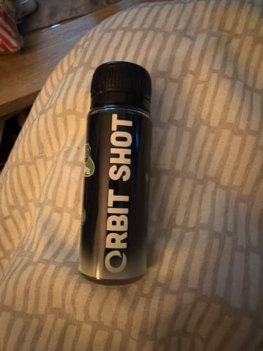 Rezensent zeigt die schwarze Flasche des Orbit Shot Nano-THC-Sirups.