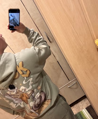 Reviewer's mirror selfie showing the graphic print on the back of their ASTROKNEE 2.0 HEAVY HOODIE DUNE.