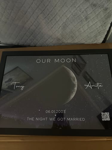 Customer's 'Our Moon' personalized poster in a black frame, showing a custom moon phase, names, and a wedding date.