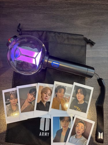 Customer's BTS Official Light Stick Ver.4, lit with a purple glow, shown with its black pouch and included photocards.