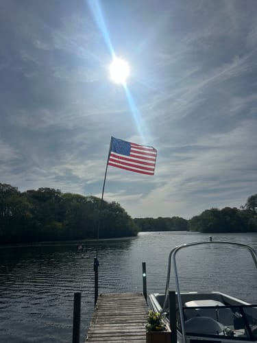 Customer's Betsy Ross Flag flying on a pole from a dock against a bright, sunny sky.