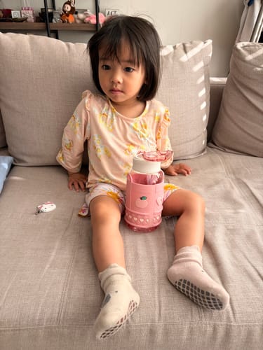 A customer's child sitting on a couch with their pink Sanrio Character Water Bottle.