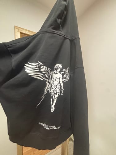 Reviewer holding up the back of a black Victory Hoodie to show the large angel graphic.