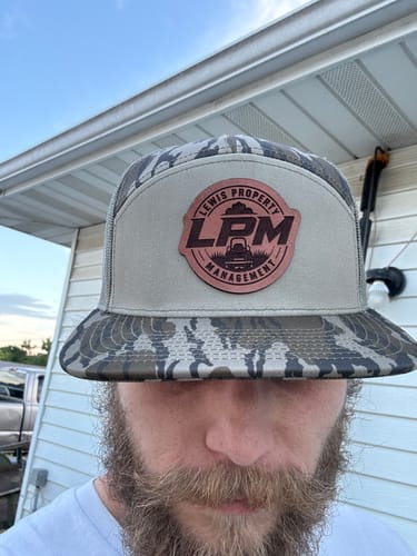 Customer wearing a camo trucker hat with a custom 'Lewis Property Management' leather patch.