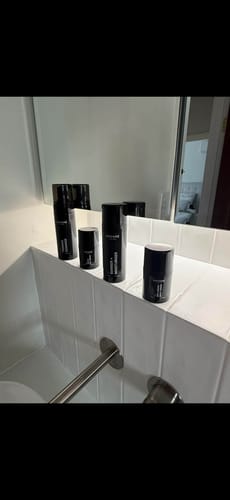 Customer's CORE FOUR HYDRATE BUNDLE products in sleek black packaging, arranged on a tiled bathroom shelf.