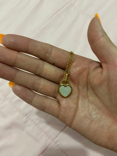 Primer plano del Collar Nyx de un cliente en la mano, mostrando el dije de corazón blanco.