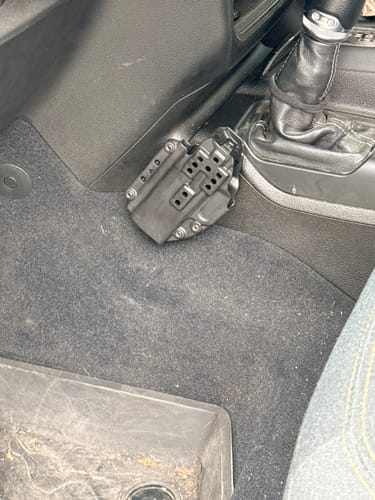 Customer's Universal Accessory Mount installed on the center console of a Jeep, holding a holster.