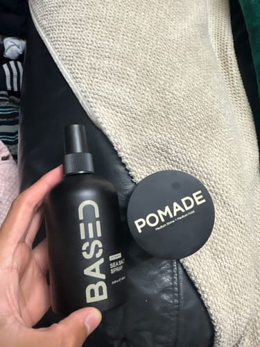 Customer holding the two black products from the Beachy Flow Duo, a sea salt spray and a pomade.