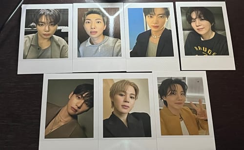 Customer's seven instant photo cards from the BTS Official Light Stick bundle laid out on a table.