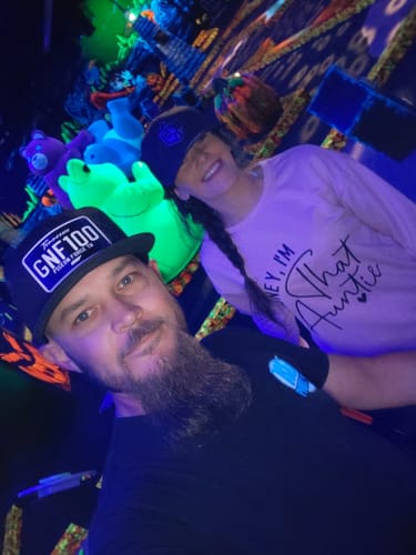 Customer wearing his custom 'GNF100' Tennessee Blackout Plate Hat with a friend in a neon-lit room.