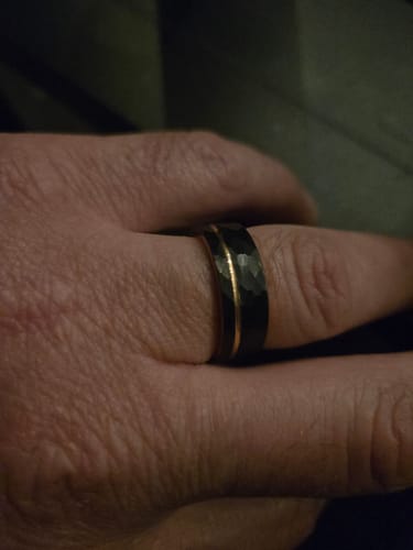 Reviewer wearing the warrantied replacement ring, a black hammered band with a gold inlay.