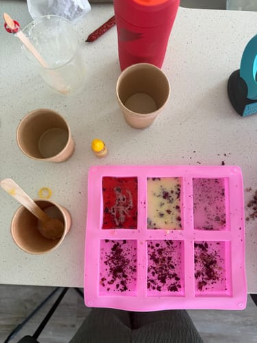 Reviewer making items from the craft subscription box, with colorful liquids and botanicals in a pink silicone mold.