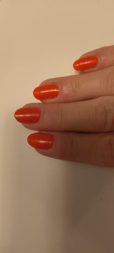 Kundin zeigt ihre gepflegten, ovalen Nägel mit den leuchtend roten 'Red Stilettos' UV Gel Wraps.