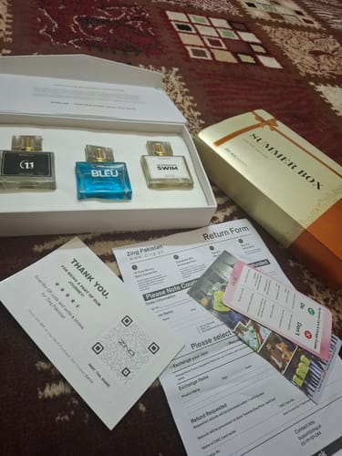 Customer's unboxed perfume bundle, showing three different fragrance bottles in a white case on a rug.