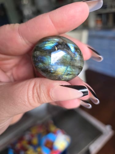 Customer's hand holding a polished, iridescent sphere from the VIP Crystal Club.