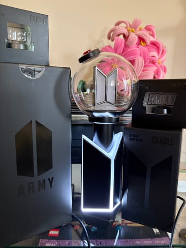 Customer's lit-up BTS Official Light Stick on its cradle, displayed with the 'ARMY' and 'PARTS' boxes.