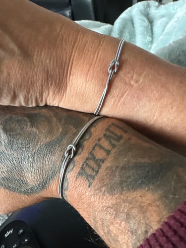 Customer shows two wrists, each wearing a silver-toned Forever Knot Bracelet.