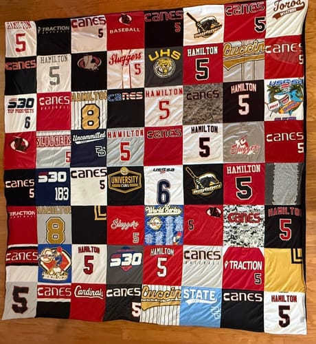 Customer's Project Repat T-Shirt Quilt made from baseball jerseys and shirts in red, black, and white, laid flat.
