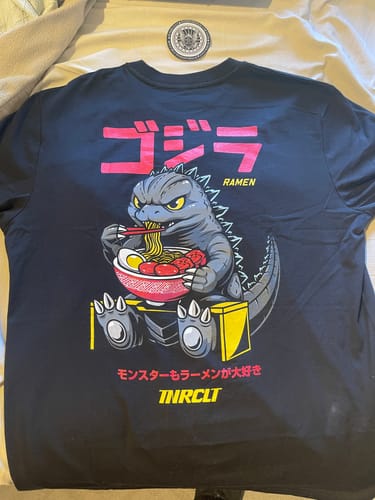 Customer's black RAMEN MONSTER TEE laid out, showing the back graphic of a monster eating ramen.