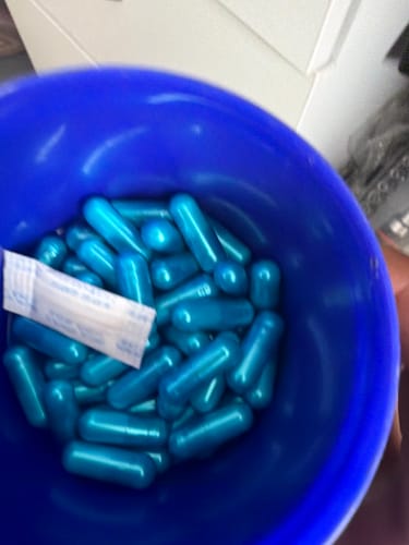 Opinión de cliente: Primer plano de las cápsulas azules de Oxandrol Eurolabspro dentro de un recipiente azul.