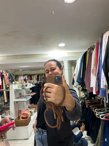 Avaliadora tira selfie no espelho com a Alça Aurora Mocha Mousse presa ao seu celular.