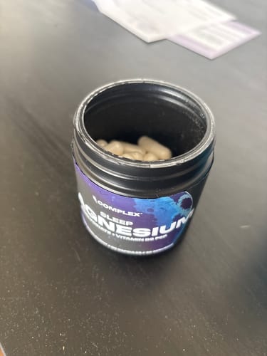 Reviewer's open black jar of Sleep Magnesium, with the capsules visible inside.
