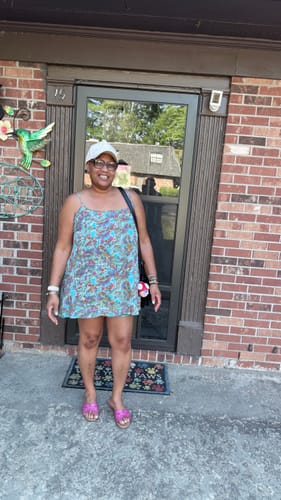 Reviewer standing outside a brick building, smiling while wearing the white baseball hat.