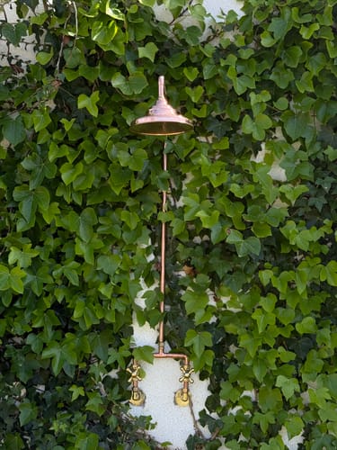 Customer's beautiful unlacquered copper outdoor shower installed against a lush, ivy-covered wall.