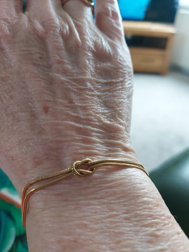 Close-up of a customer's wrist, showing the delicate gold-colored Forever Knot Bracelet.