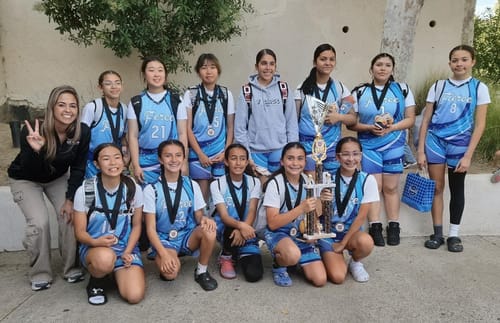 Customer's basketball team posing outdoors wearing the custom light blue and purple galaxy pattern jerseys and holding a trophy.