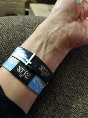 Customer's wrist wearing the Heaven Holds You Bracelet with a white cross charm.