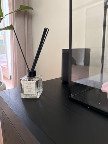 Recensent's Istanbul geurstokjes staand op een donker houten meubel in huis.