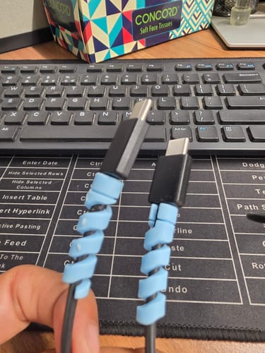 Customer's hand holding two cables with light blue spiral Cable Protectors attached.