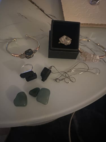 Un client présente ses pierres d'aventurine vertes avec plusieurs autres bijoux en pierre sur une table.