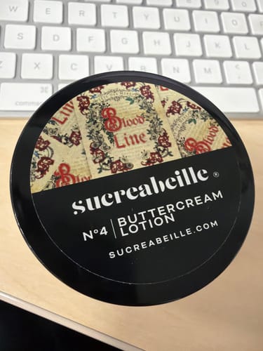 Customer's round, black jar of Buttercream Lotion, with the "Blood Line" scent label visible on the lid.