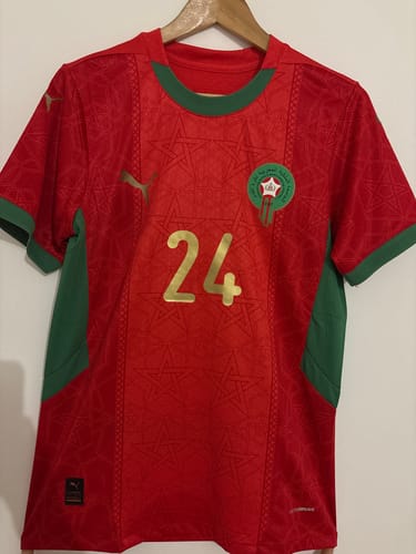 Client montrant son maillot du Maroc domicile rouge et vert, accroché sur un cintre, avec le flocage personnalisé du numéro 24.