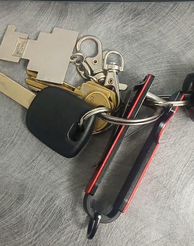 Customer's black and red key holder attached to a large set of keys on a metal surface.