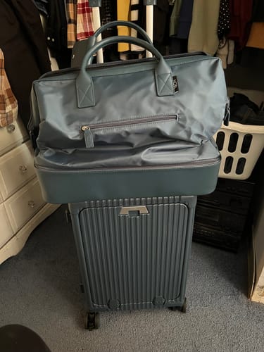 Reviewer's blue All-in-One Carry-On with a matching duffel bag on the handle in a room.