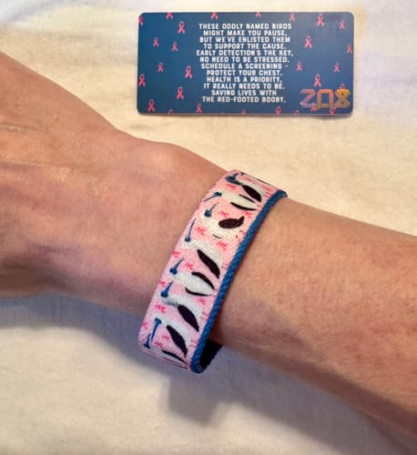Customer showing the Save the Boobies Bracelet on their wrist, with its detailed bird and ribbon pattern.