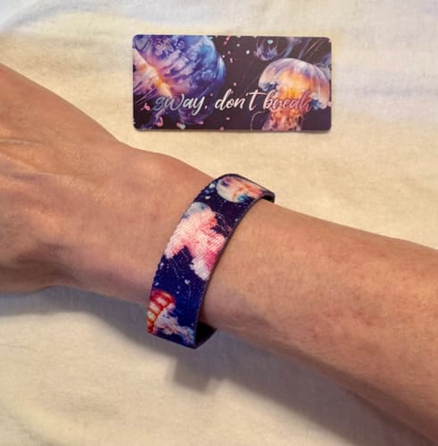 Customer wearing the 'Sway, Don't Break' Goldie Mystery ZOX bracelet on their wrist, with the matching collector's card nearby.