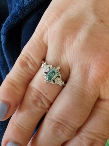 Customer's hand wearing the vintage moissanite ring with a peacock blue center stone.