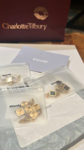 Customer's Celine Clover Bracelets in gold, white, and black shown in small clear bags upon arrival.