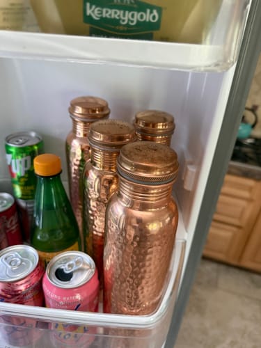 Reviewer's four hammered copper water bottles stored together in a refrigerator door.