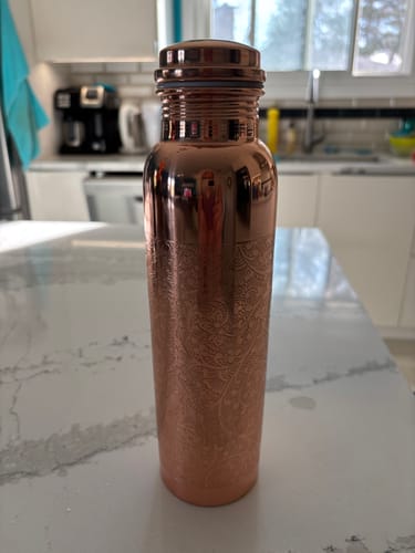 Customer's Mandala Engraved Copper Water Bottle displayed on their kitchen counter.