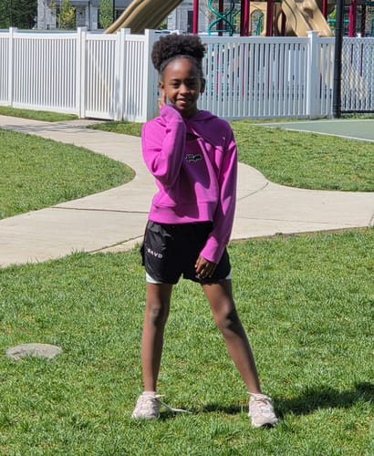 Reviewer's granddaughter posing outdoors in the black 'Wonderfully Made' Girls Performance Shorts.