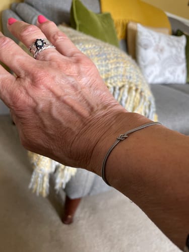 Close-up of a reviewer wearing the simple Forever Knot Bracelet on their wrist.