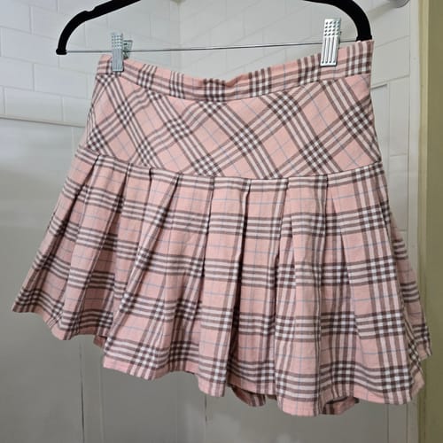 Customer's pilled Girly Plaid Pleated High Rise Skirt in pink hanging on a hanger.