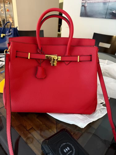 Customer's bright red Warkin Bag with pebbled leather and gold hardware, sitting on a table.